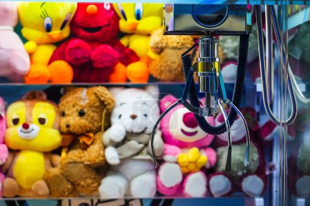Photo for Toy crane vending machine, claw game or cabinet to catch the toys. Shopping, holiday activity, game of chance. Selective focus on crane - Royalty Free Image
