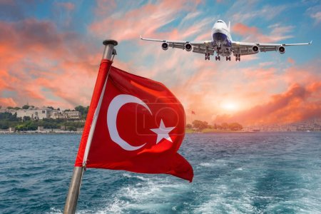 Foto de Ondeando bandera turca en un ferry contra el Bósforo o el Estrecho de Estambul y el avión de vuelo aterrizaje aeropuerto cielo puesta del sol. - Imagen libre de derechos