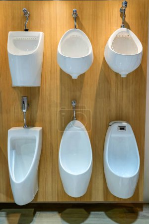 Exhibition of samples urina toilet bowls in a row in the wall warehouse of a plumbing store. Modern sanitary ware product for hygiene