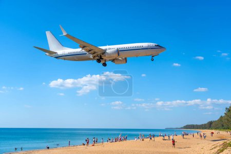 Airplane landing above beautiful beach with people on the beach and sea, travel.