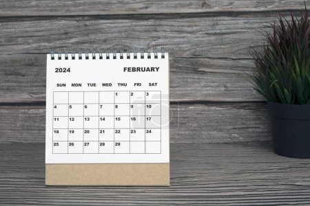 Foto de Blanco febrero 2024 calendario en escritorio de madera con maceta. 2024 Concepto de Año Nuevo - Imagen libre de derechos