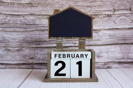 Foto de Pizarra con fecha de calendario 21 de febrero en bloque de cubo blanco en mesa de madera. - Imagen libre de derechos