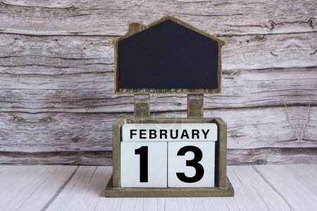 Photo for Chalkboard with February 13 calendar date on white cube block on wooden table. - Royalty Free Image