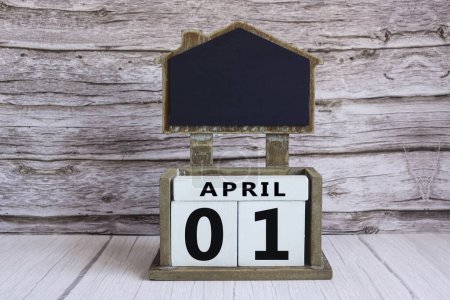 Téléchargez les photos : Tableau noir avec date de calendrier Avril 01 sur bloc cube blanc sur table en bois. - en image libre de droit