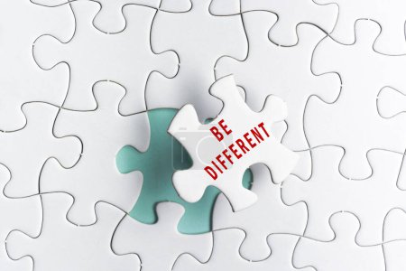 Photo for Be different text on white Jigsaw Puzzle over green background. - Royalty Free Image