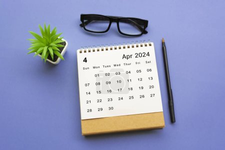 Avril 2024 calendrier de bureau avec plante en pot, stylo et lunettes de lecture sur fond bleu.
