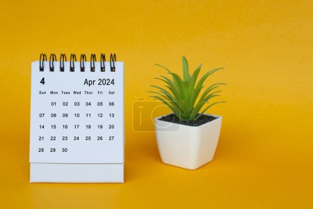 Schreibtischkalender April 2024 mit Topfpflanze auf gelbem Hintergrund. Kopierraum.