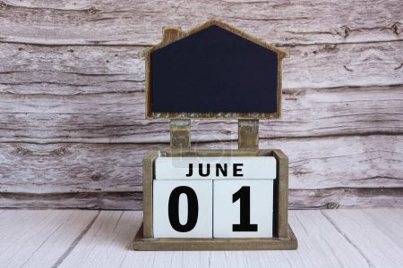Téléchargez les photos : Tableau noir avec date de calendrier juin 01 sur bloc cube blanc sur table en bois. - en image libre de droit