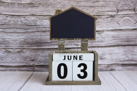 Téléchargez les photos : Tableau noir avec date de calendrier juin 03 sur bloc cube blanc sur table en bois. - en image libre de droit