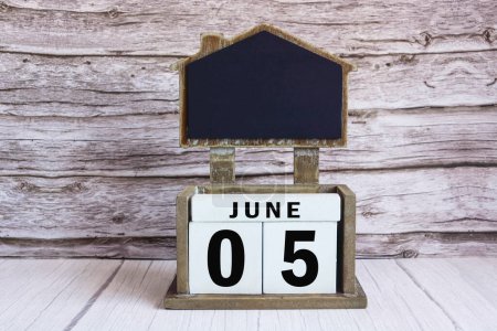Kreidetafel mit 05. Juni Kalenderdatum auf weißem Würfelblock auf Holztisch.