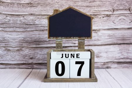 Pizarra con fecha de calendario 07 de junio en bloque de cubo blanco en mesa de madera.