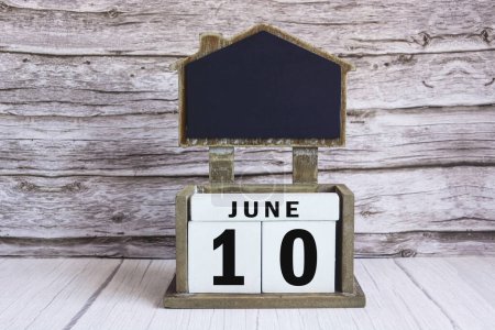 Tableau noir avec date du calendrier du 10 juin sur bloc de cube blanc sur table en bois.