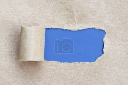 Brown paper with torn hole and rolled edge with blue background.