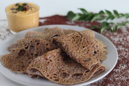 Téléchargez les photos : Instant Finger Millet Dosa, made with finger millet flour, curd and spices. Served with coconut chilly condiment. Easy and healthier alternative to rice based fermented crepe. Shot on white background - en image libre de droit