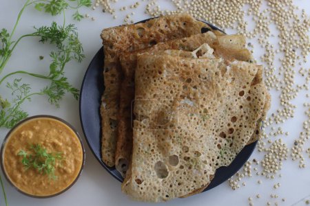 Foto de Instant Jowar dosa is a quick and easy Indian breakfast dish, made with jowar flour by mixing it with water and cooked on a preheated non stick pan. Served with coconut chilly spicy condiment - Imagen libre de derechos