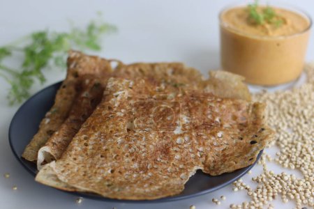 Téléchargez les photos : Instant Jowar dosa is a quick and easy Indian breakfast dish, made with jowar flour by mixing it with water and cooked on a preheated non stick pan. Served with coconut chilly spicy condiment - en image libre de droit