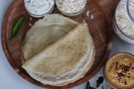 Photo for Instant oats poha dosa served with spicy coconut condiment. Non fermented thin instant crepe recipe made of oats, flattened rice and yogurt. An instant version of favourite Indian dish called dosa - Royalty Free Image