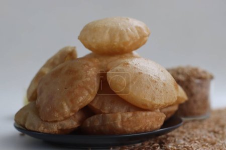 Photo for Khapli wheat puris. Deep fried Indian flatbread made of emmer wheat flour. A version of puri with oldest wheat varieties of India. Shot along with a heap of khapli wheat on white background - Royalty Free Image
