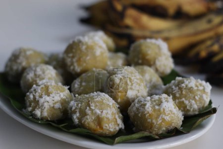 Photo for Plantain dumpling or Kozukatta. Steamed rice dumpling in banana leaf made with a rice flour dough mixed with mashed ripe plantain and sweet coconut filling inside. Shot along with ripe plantains - Royalty Free Image