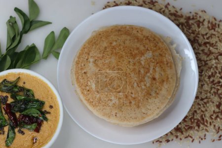 Photo for Rajamudi rice pancakes or soft dosa made of a fermented batter of the rice and coconut served with spicy coconut chutney. Rajamudi is a variety of red rice that was grown for the Maharajas of Mysore - Royalty Free Image