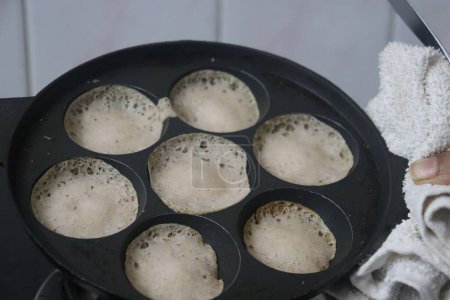 Foto de Apéndice de arroz Rajamudi en tamaño miniatura. Mini tolvas o mini appam o crepes atados en tamaño miniatura preparados en el mini molde de unniappam chatti o appe pan con masa fermentada de arroz rajamudi - Imagen libre de derechos