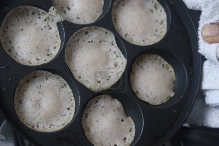 Foto de Apéndice de arroz Rajamudi en tamaño miniatura. Mini tolvas o mini appam o crepes atados en tamaño miniatura preparados en el mini molde de unniappam chatti o appe pan con masa fermentada de arroz rajamudi - Imagen libre de derechos
