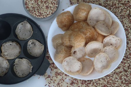 Foto de Rajamudi arroz Mini tolvas o mini appam tiro con la cacerola de appe. Appam hecho con masa fermentada de arroz rajamudi en tamaño miniatura preparado en el mini molde de unniappam chatti o appe pan. - Imagen libre de derechos