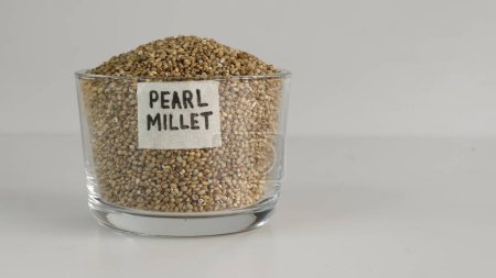 Photo for Pearl millet grains in a glass bowl with label on it filled to the brim, showcasing their pearl like natural beauty and healthy nutrition. Ideal for food and agriculture concepts. - Royalty Free Image