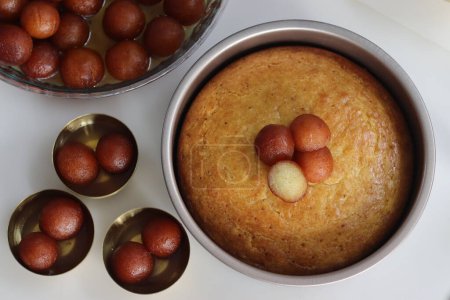 Téléchargez les photos : Gâteau Gulab Jamun dans une boîte à gâteau. Dessert fusion irrésistible, combinant des saveurs riches de bonbons indiens traditionnels avec l'indulgence d'un gâteau humide. Parfait pour les célébrations et les occasions festives - en image libre de droit