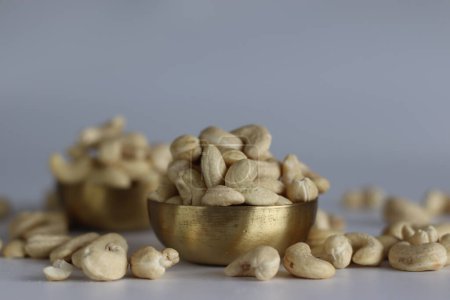 A heap of golden roasted cashews in a brass bowl. Perfect for snacks and culinary delights, capturing the essence of premium quality and irresistible flavor. Shot on white background