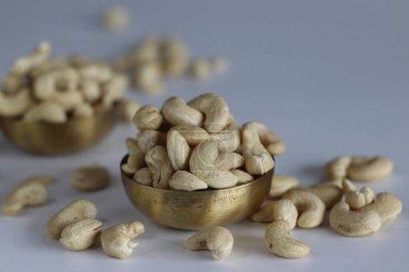 A heap of golden roasted cashews in a brass bowl. Perfect for snacks and culinary delights, capturing the essence of premium quality and irresistible flavor. Shot on white background