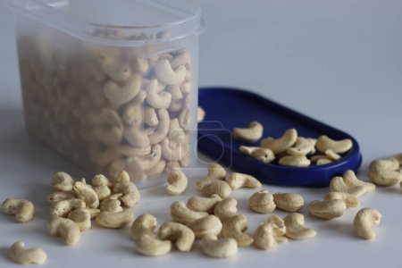 A heap of golden roasted cashews in a plastic container. Perfect for snacks and culinary delights, capturing the essence of premium quality and irresistible flavor. Shot on white background