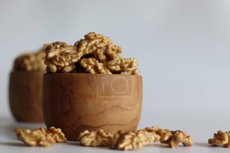 Pristine pile of premium dry walnuts in a wooden bowl, ideal for culinary creations and healthy snacks. Nut lovers rejoice in this bountiful harvest. Rustic, organic. Shot on white background