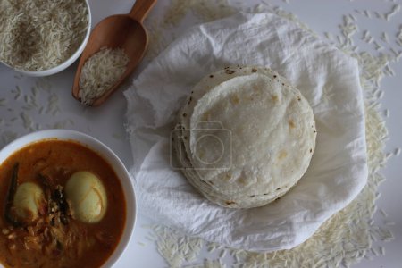 Reis Roti serviert mit Ei-Curry. Eine glutenfreie Alternative mit rohem Reis vier, perfekt für eine gesunde Mahlzeit. Indische Küche, Fladenbrot, Vollkornprodukte, traditionelles Ernährungskonzept. Schuss auf weißem Hintergrund