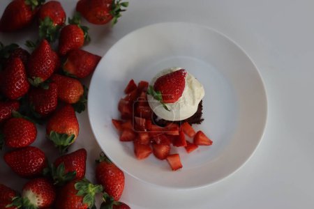 Schokoladenbrownie mit frischen Erdbeeren und einer Kugel cremigem Vanilleeis, perfekt für Dessertmenüs und süßen Heißhunger. Mit Ei weniger Vorbereitung von Brownie. Schuss auf weißem Hintergrund