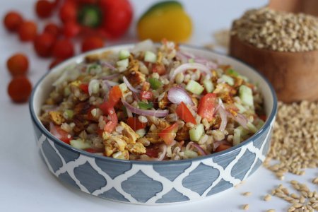 Hulled barley chicken salad. Hearty salad with hulled barley, chicken, cucumber, tomato, onions in a ceramic bowl. Healthy, nutritious, delicious meal for food lovers. Shot on white background