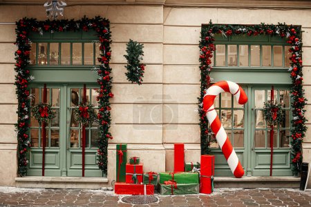 Téléchargez les photos : Grandes cannes à bonbons élégantes, cadeaux de Noël enveloppés de rouge et de vert, branches de sapin, couronnes sur l'extérieur du bâtiment. Décor de Noël moderne dans la rue de la ville. Vacances d'hiver en Europe. Joyeux Noël - en image libre de droit