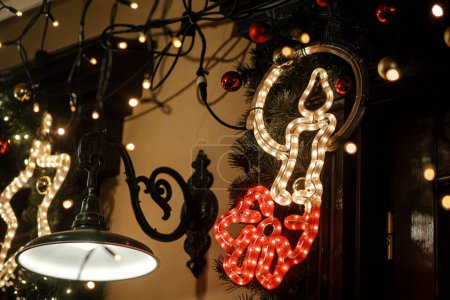 Téléchargez les photos : Élégante illumination de bougie de Noël et lumières festives sur les branches de sapin en soirée en plein air. Décor de Noël moderne dans la rue de la ville. Vacances d'hiver atmosphériques en Europe. Joyeux Noël! - en image libre de droit