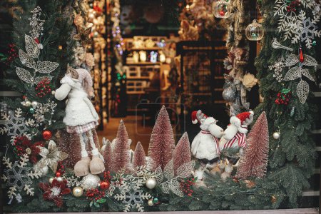 Photo for Stylish christmas pink trees, branches with baubles and reindeers toys store, festive showcase of shop. Modern christmas decor in city street. Winter holidays in Europe. Merry Christmas - Royalty Free Image