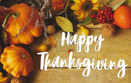 Glückwunschkarte zum Thanksgiving. Happy Thanksgiving Text auf stilvollen Kürbissen, Herbstblumen, Beeren und Nüssen Komposition auf rustikalen Holztisch. Handschriftlicher Schriftzug
