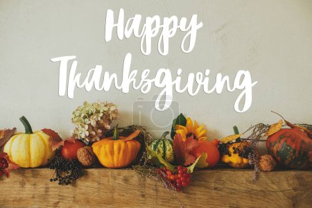 Photo for Happy Thanksgiving greeting card. Happy Thanksgiving text on pumpkins, flowers, berries, nuts composition on rustic wood on fireplace. Handwritten lettering - Royalty Free Image