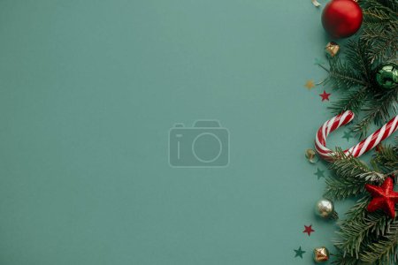 Foto de ¡Feliz Navidad! Elegante borde de Navidad con decoraciones festivas, confeti, ramas de abeto sobre fondo verde. Navidad plana laico, temporada tarjetas de felicitaciones plantilla, espacio para el texto - Imagen libre de derechos