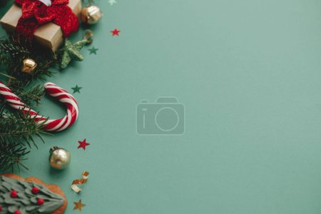 Téléchargez les photos : Joyeux Noël ! Bannière de Noël moderne. Élégante bordure de Noël avec des décorations festives, confettis, branches de sapin, cadeau sur fond vert. Saisons modèle de carte de voeux, espace pour le texte - en image libre de droit