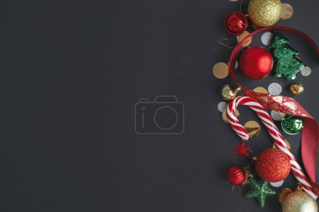 Photo for Stylish christmas candy cane, confetti and festive decorations border on black background. Modern christmas flat lay, space for text. Season's greetings card. Merry Christmas and Happy Holidays! - Royalty Free Image