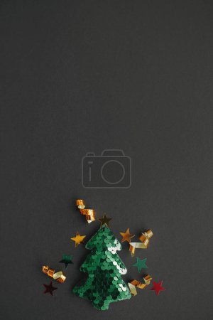 Photo for Christmas tree modern minimal flat lay, winter holidays concept. Stylish little christmas tree with sparkling gold confetti on black background. Merry Christmas! Space for text. Creative idea - Royalty Free Image
