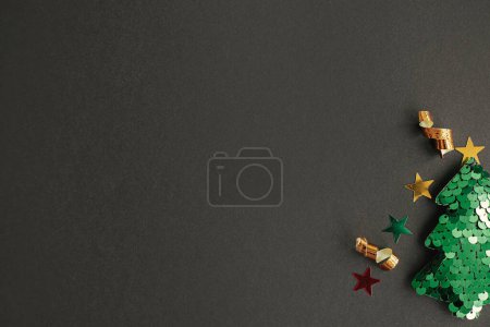 Foto de ¡Feliz Navidad! Elegante pequeño árbol de Navidad con confeti de oro brillante sobre fondo negro. Moderno piso festivo con espacio para el texto. Una idea creativa. Banner de vacaciones de invierno - Imagen libre de derechos