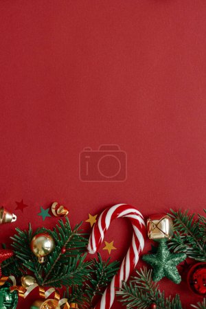 Téléchargez les photos : Joyeux Noël ! Pose appartement moderne de Noël. Boules de Noël élégantes, branches de sapin, confettis et canne à bonbons sur fond rouge. Modèle de carte de voeux Saisons, espace pour le texte. Vacances d'hiver - en image libre de droit
