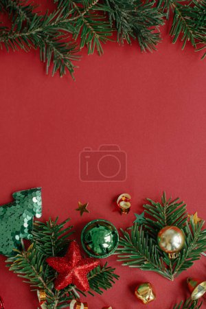 Foto de Feliz Navidad! Moderna cama plana de Navidad. Elegantes adornos navideños, ramas de abeto, confeti y árbol sobre fondo rojo. Plantilla de tarjeta de felicitación Seasons, espacio para texto. Vacaciones de invierno - Imagen libre de derechos