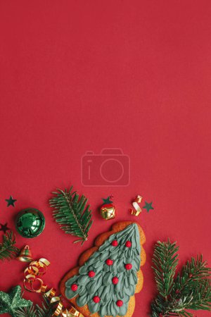 Téléchargez les photos : Appartement de Noël moderne laïc. Biscuit d'arbre de Noël élégant, boules, branches de sapin, confettis sur fond rouge. Carte de vœux des saisons, espace pour le texte. Joyeux Noël ! Vacances d'hiver - en image libre de droit