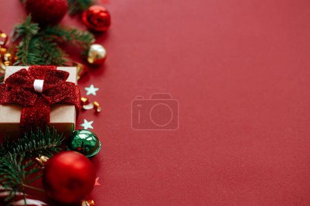 Photo for Modern christmas composition. Stylish christmas gift, baubles, fir branches, confetti on red background. Seasons greeting card, space for text. Merry Christmas! Winter holidays banner - Royalty Free Image